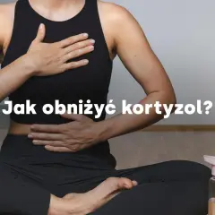 Kobieta w pozycji medytacyjnej, z dłońmi na brzuchu i klatce piersiowej, pokazuje jak obniżyć kortyzol.