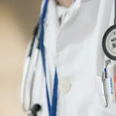 Lekarz w białym fartuchu ze stetoskopem i przyborami. Zwróć uwagę na kwasica mleczanowa objawy, gdy coś Cię niepokoi.