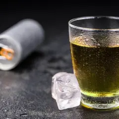 Szklanka z napojem energetycznym i kostki lodu. Czy tauryna pobudza? Ten napój może pomóc.