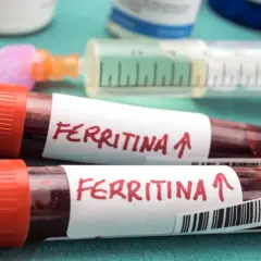 Dwie probówki z krwią oznaczone "Ferritina" i strzałką w górę, sugerujące potrzebę podniesienia ferrytyny. Obok strzykawka i fiolki.
