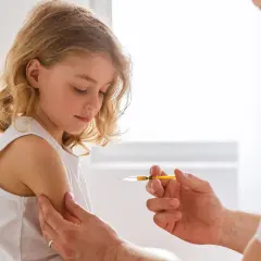 Dziewczynka otrzymuje szczepionkę na tężec. Lekarz podaje zastrzyk w ramię dziecka, zapewniając mu ochronę.