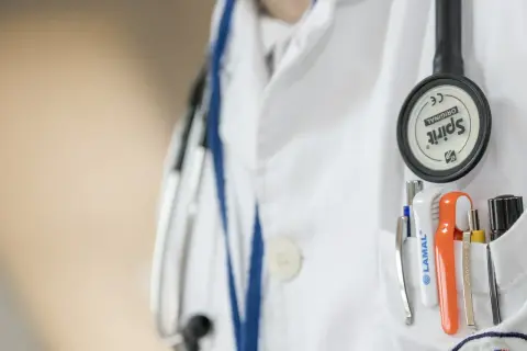 Lekarz w białym fartuchu ze stetoskopem i przyborami. Zwróć uwagę na kwasica mleczanowa objawy, gdy coś Cię niepokoi.