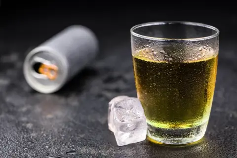 Szklanka z napojem energetycznym i kostki lodu. Czy tauryna pobudza? Ten napój może pomóc.