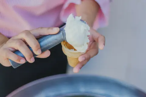 Nakładanie lodów do wafelka. Może to być ulga na ból gardła, gdy jest zimno i słodko.
