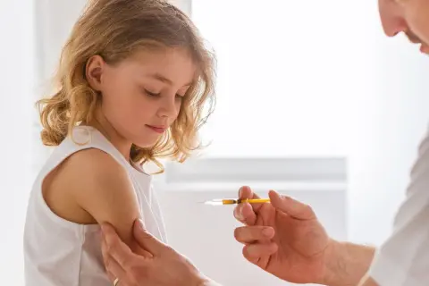 Dziewczynka otrzymuje szczepionkę na tężec. Lekarz podaje zastrzyk w ramię dziecka, zapewniając mu ochronę.